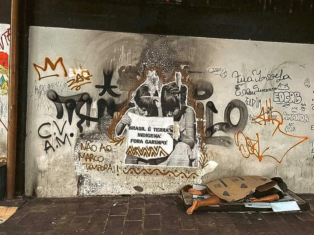 In Manaus, Brazil, Comando Vermelho markings share a wall with an indigenous rights poster. An image that captures the tensions coexisting in the Amazon. Photo: Crisis Group / Bram Ebus, September 2023.