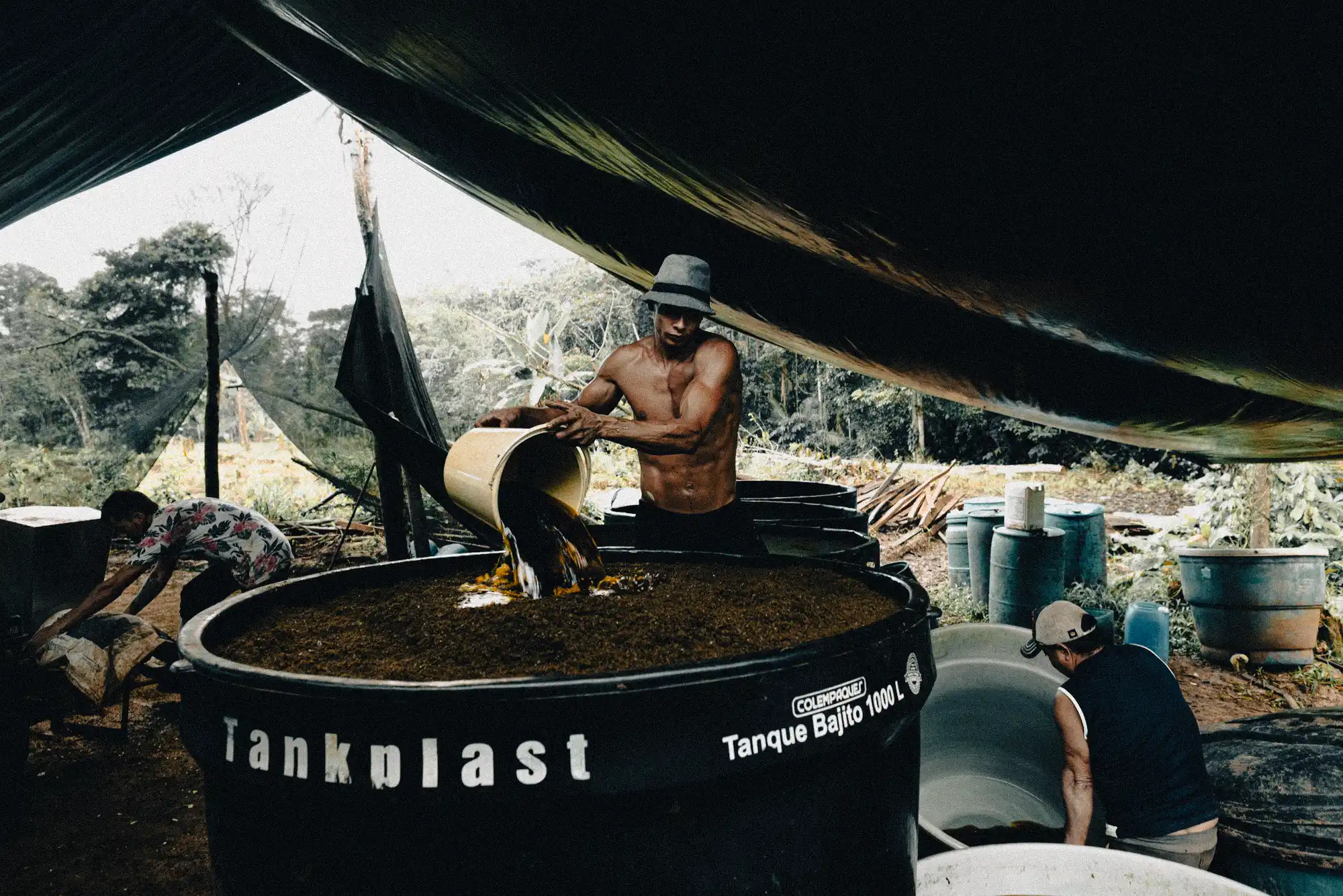 A worker mixing coca leaves with chemicals in a maceration tank, the first step in producing cocaine base paste. Photo: Tom Laffay