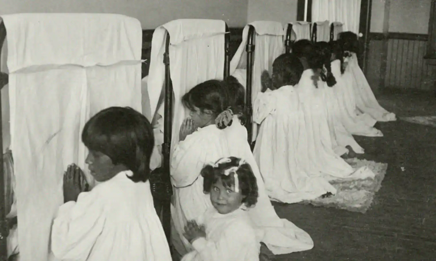 Indigenous girls praying at the Phoenix Indian School, Arizona. The imposition of Christianity was a central part of the program at these boarding schools. Photo: U.S. National Archives and Records Administration.