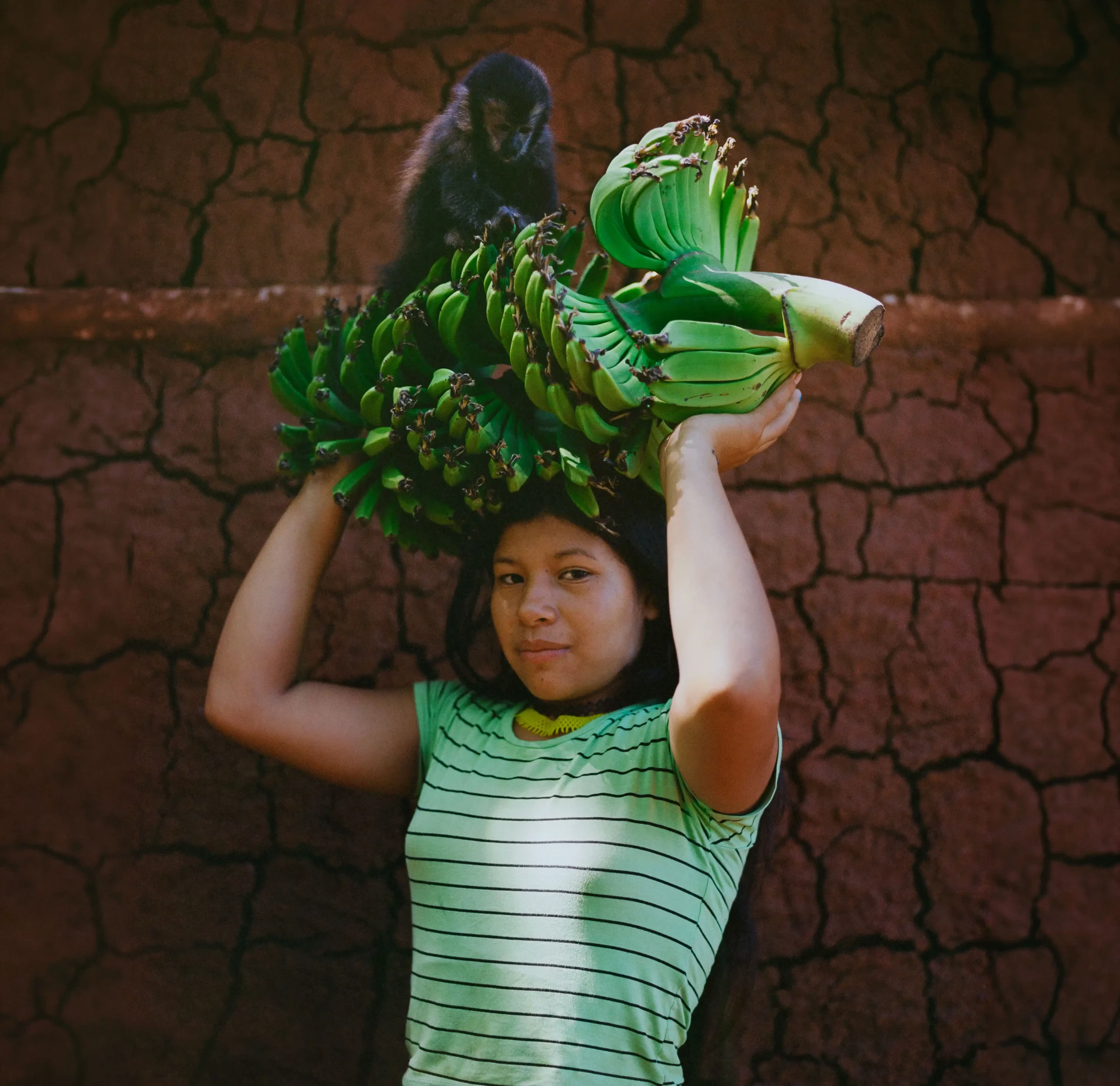 Shared nature. Portrait of Analía Castillo holding banana fruits alongside a monkey. The communal, collective and shared is fundamental to understanding their worldview. Photo: Mauricio Holc